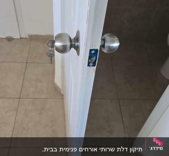 דלת לבנה פתוחה עם ידית מתכת ומפתח